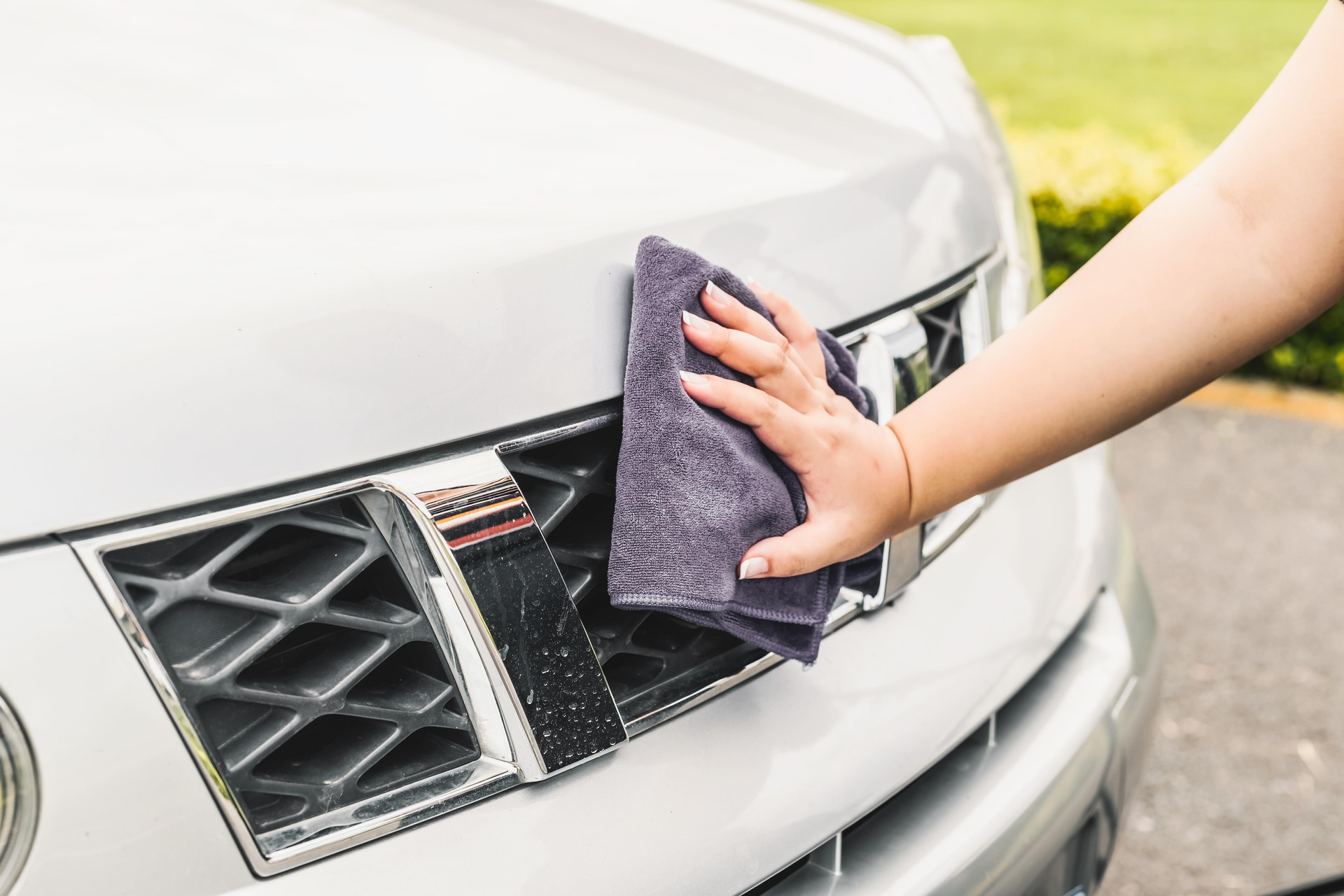 A woman cleaning a car with a microfiber cloth